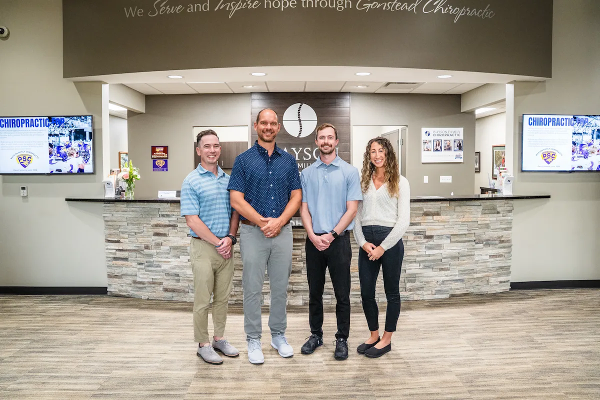 Wayson Family Chiropractic team photo with all the doctors of chiropractic standing in front of front desk