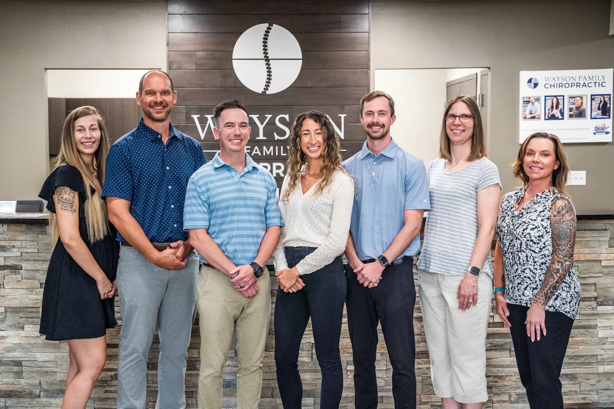 Wayson Family Chiropractic team standing professionally in front of the reception area in Cedar Falls