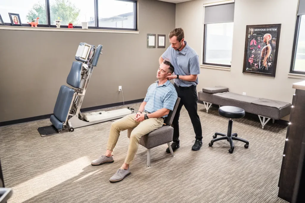 Dr. Britton Goldsmith performing a neck adjustment while the patient is sitting up