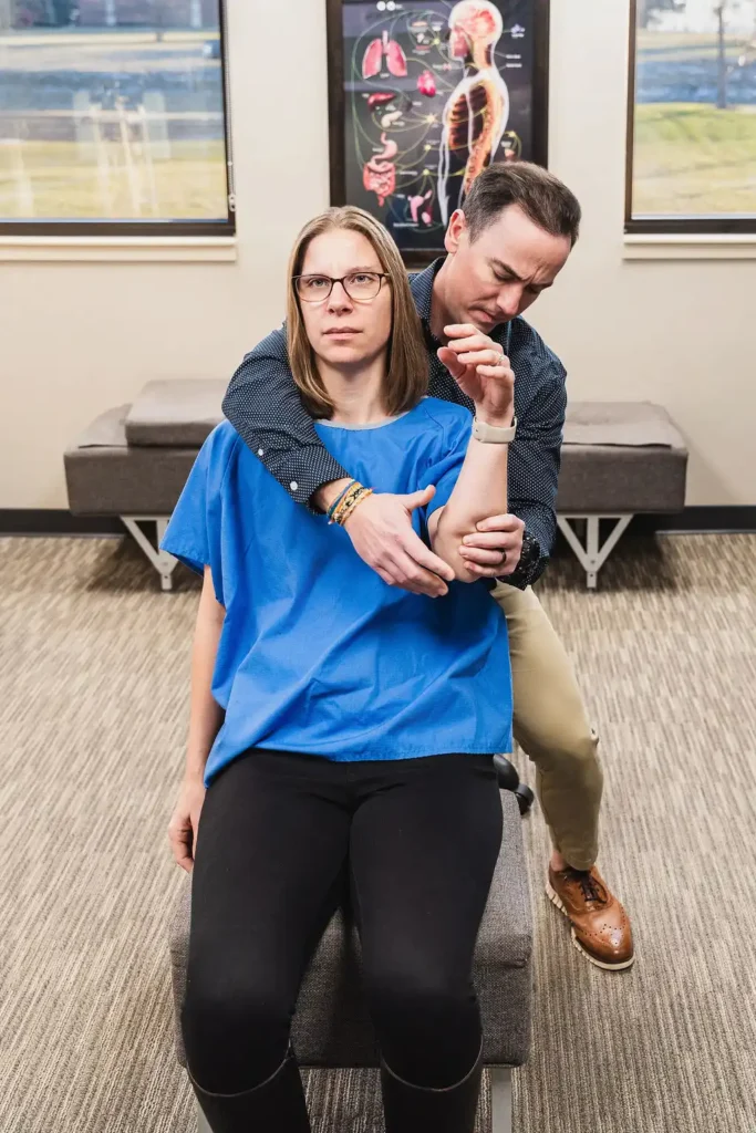 Dr. Thad Fever adjusting the shoulder for a female chiropractic patient