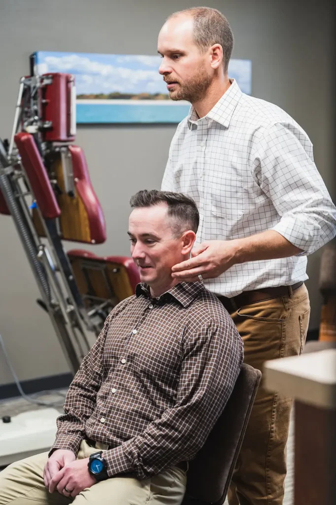 Dr. Blake Wayson checking the subluxations on a male patient sitting up in a chair