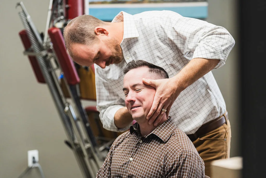 Dr. Blake Wayson about to perform a neck adjustment on a chiropractic patient