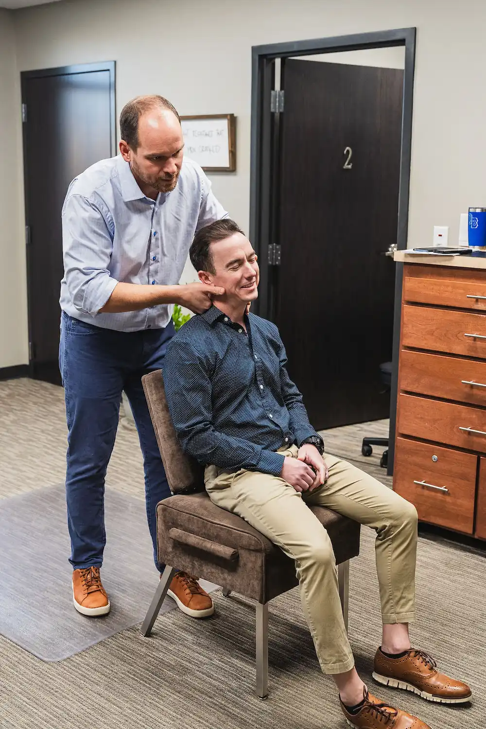Dr. Blake Wayson adjusting a male patient's neck while he sits up
