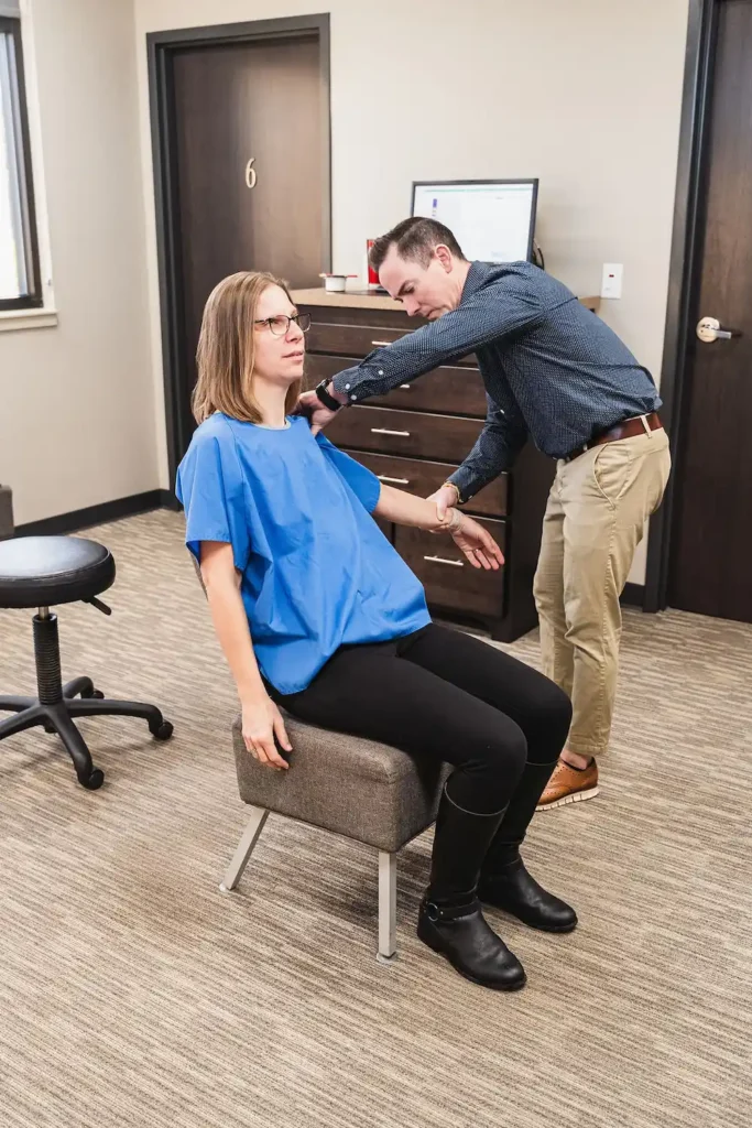Dr. Thad Fever checking shoulder rotation on female chiropractic patient
