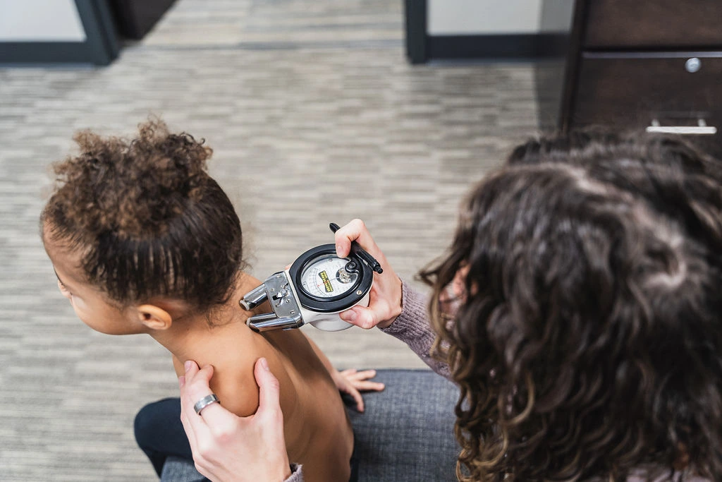 Dr. Sara Cahill using Gonstead nervo-scope to measure the spine health of a young girl