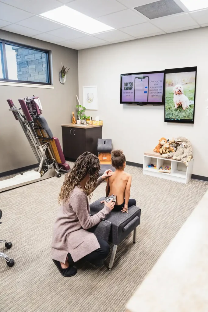 Dr. Sara Cahill using Gonstead nervo-scope to measure the spine health of a young girl sitting on a chair
