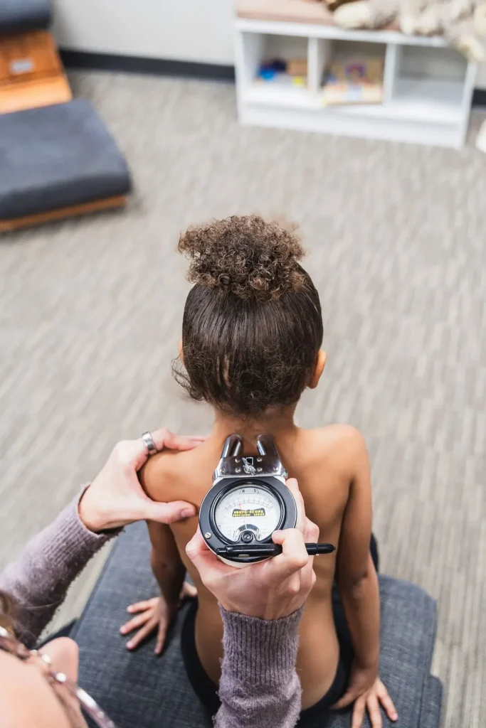 Dr. Sara Cahill using Gonstead nervo-scope to measure the spine health of a young girl in the neck region