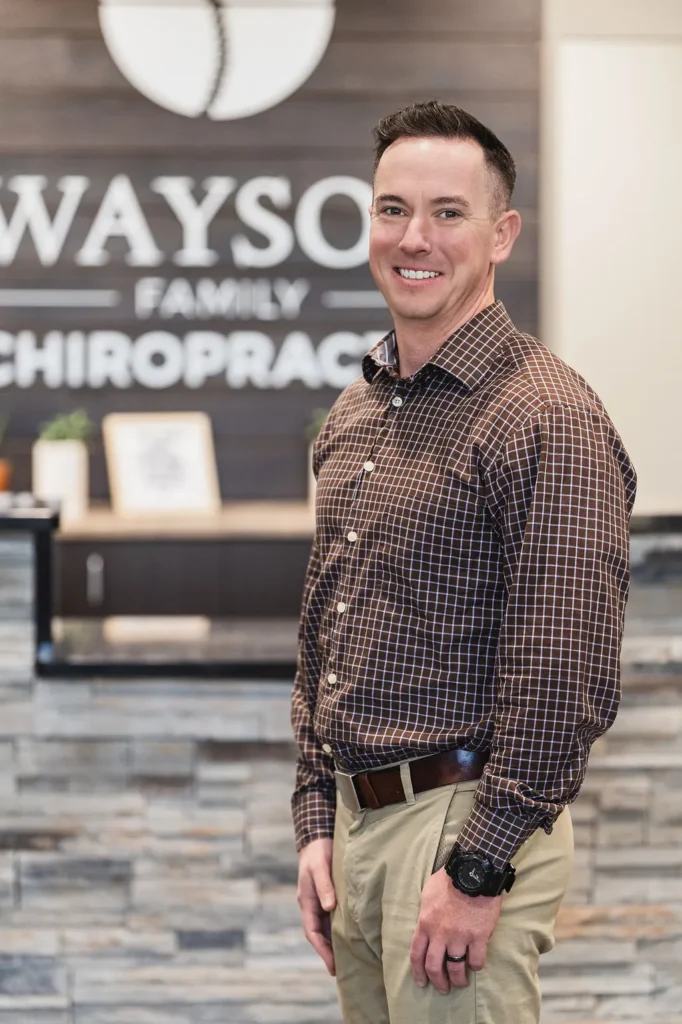 Dr. Thad looking professional standing in front of reception at Wayson Family Chiropractic