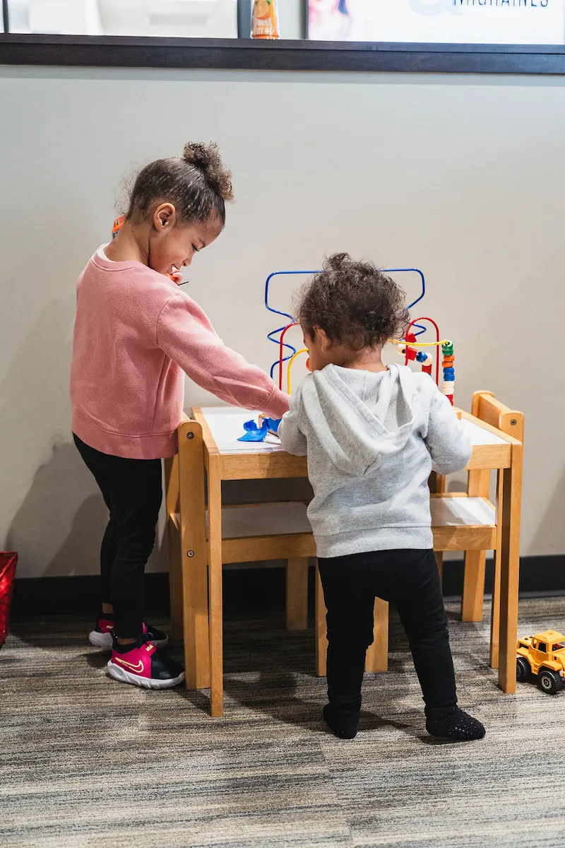 Two young kids playing with toys at Wayson Family Chiropractic smiling