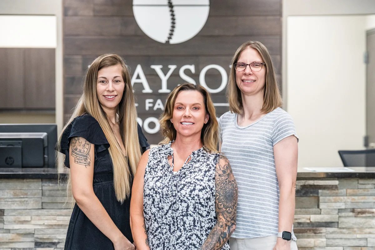 Wayson Family Chiropractic staff smiling together in front of receptionist area