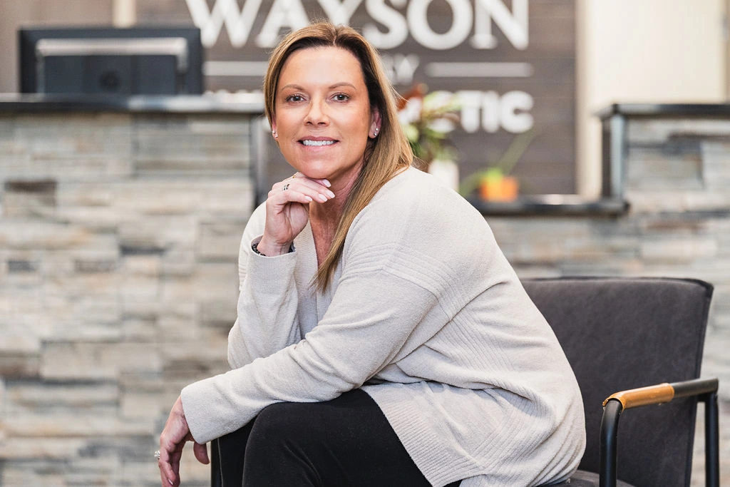 Wayson Family Chiropractic team member smiling in clinic lobby while seated