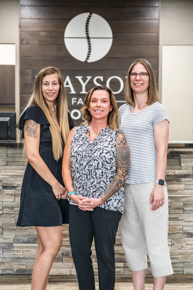 Wayson Family Chiropractic staff smiling together looking professional in front of office greeting area for new patients