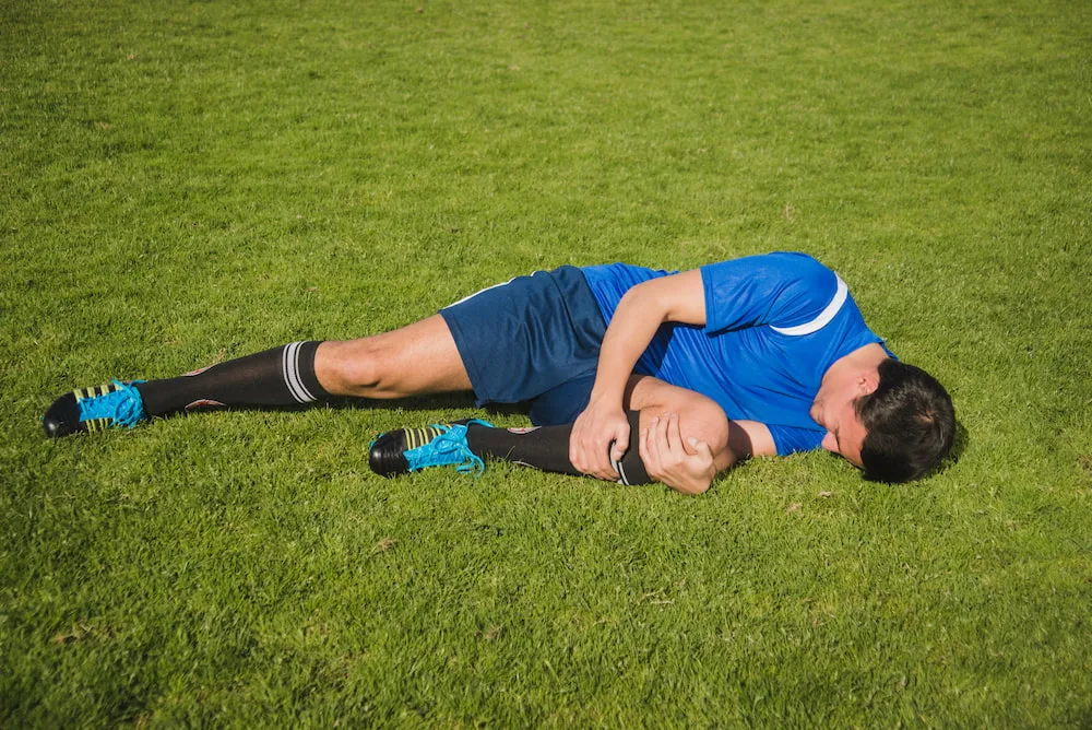 Football player holding knee after game injury