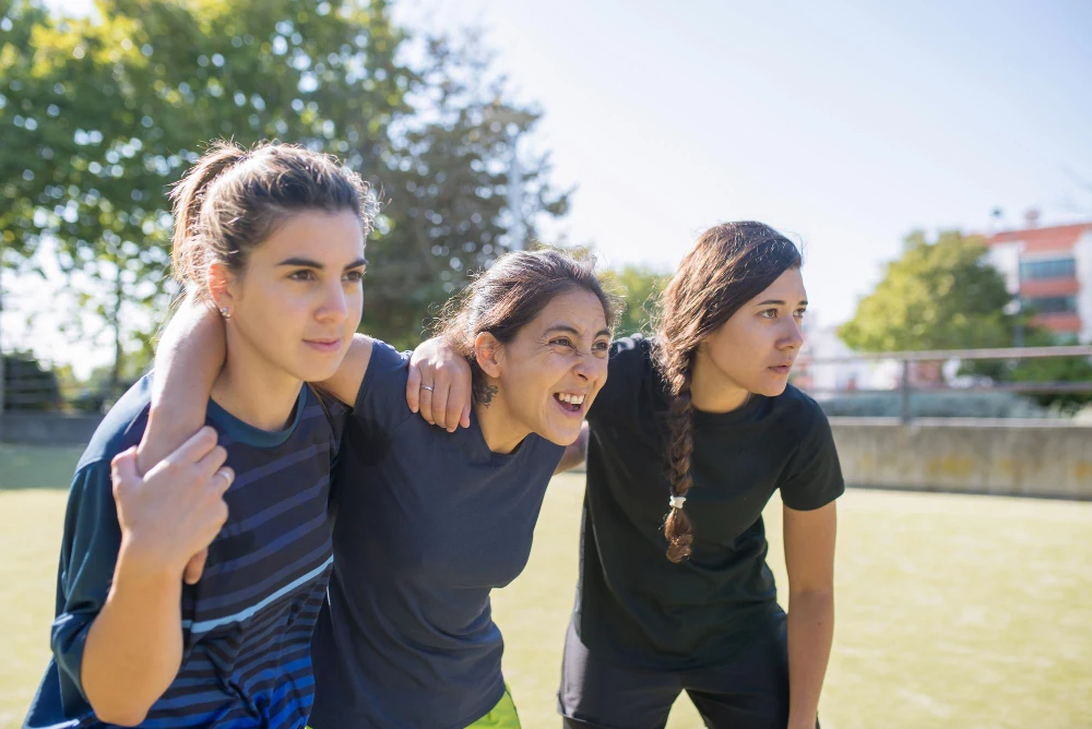 Three young female athletes standing on football field before practice