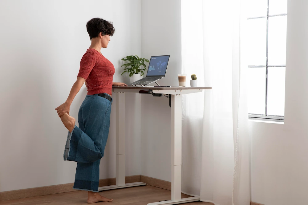 Office worker adjusting posture while using standing desk
